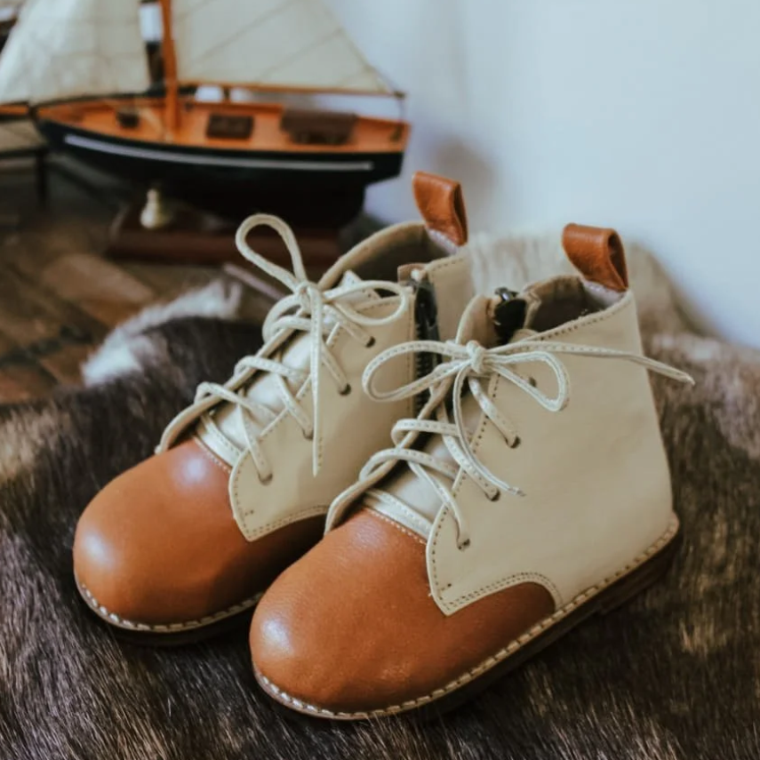 Pair of tan and brown leather boots on a textured surface with a blurred background