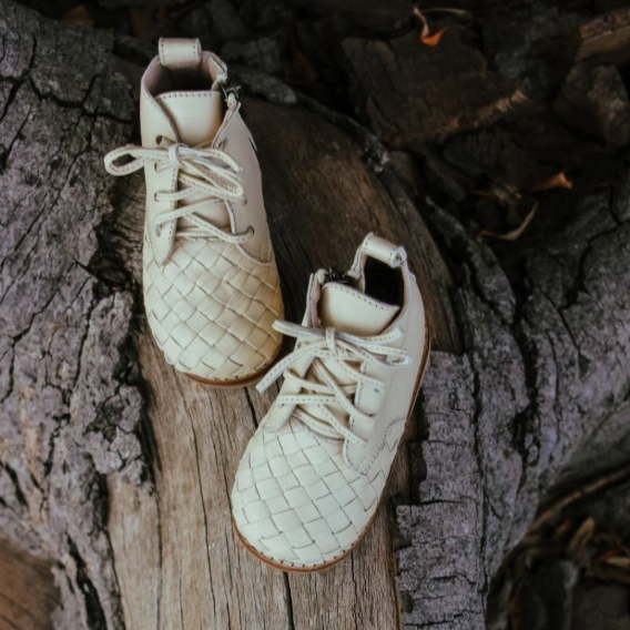 Pair of beige leather shoes with woven pattern on a wooden surface