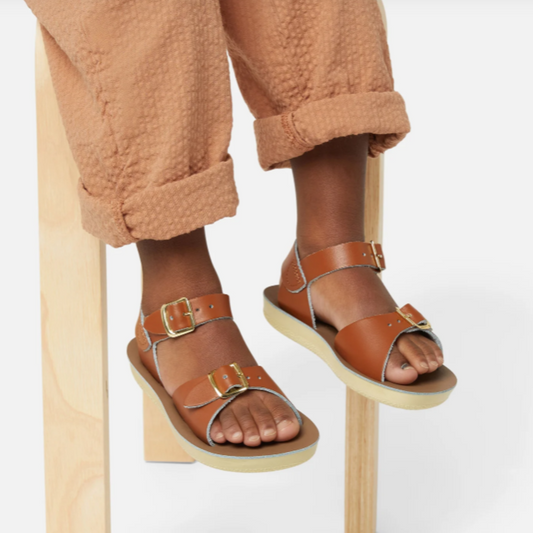Brown sandals with buckles worn by a person on a white background