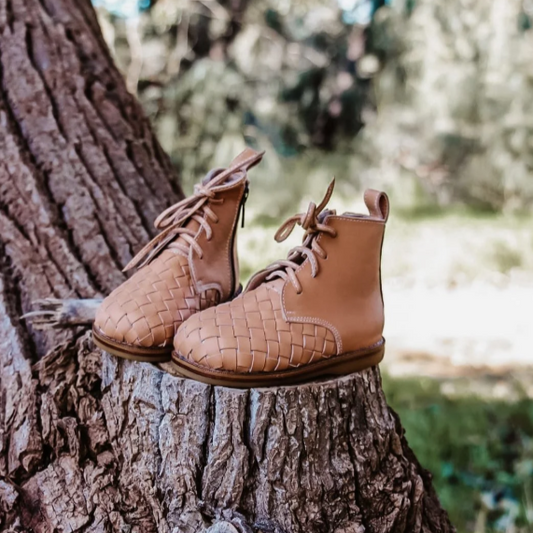 Pair of tan leather boots on a tree stump with a natural background