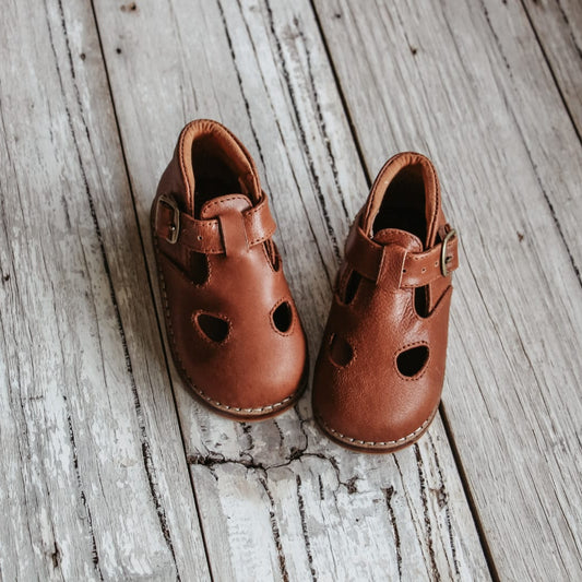 Pair of brown sandals on a wooden surface