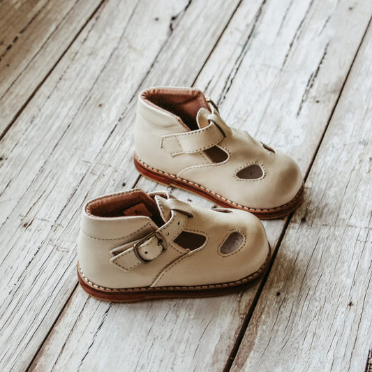 Pair of beige children's shoes on a wooden floor