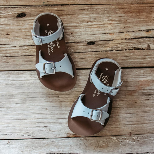Pair of brown and white sandals on a wooden surface
