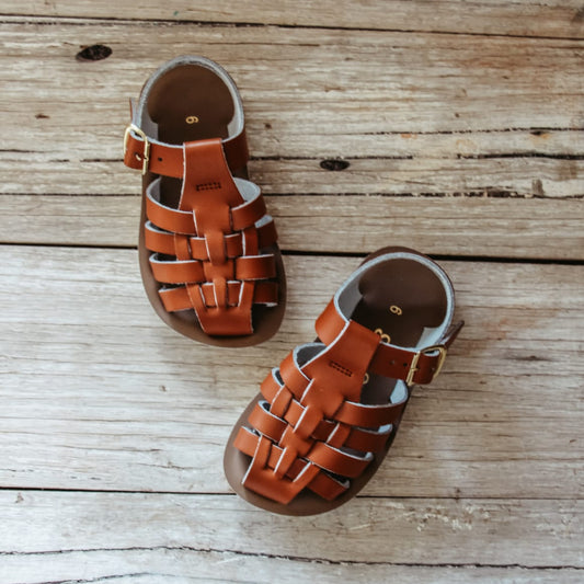 Pair of brown sandals on a wooden surface
