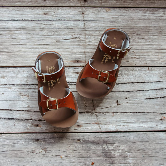 Pair of brown sandals with buckles on a wooden surface