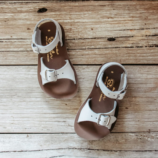 Pair of brown and white sandals on a wooden surface